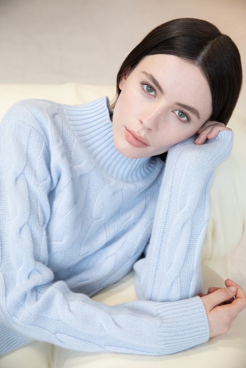 A woman with dark hair wears a blue sweater as an everyday joy design choice. 