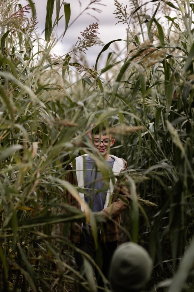 A boy in a jacket walks through a corn maze.