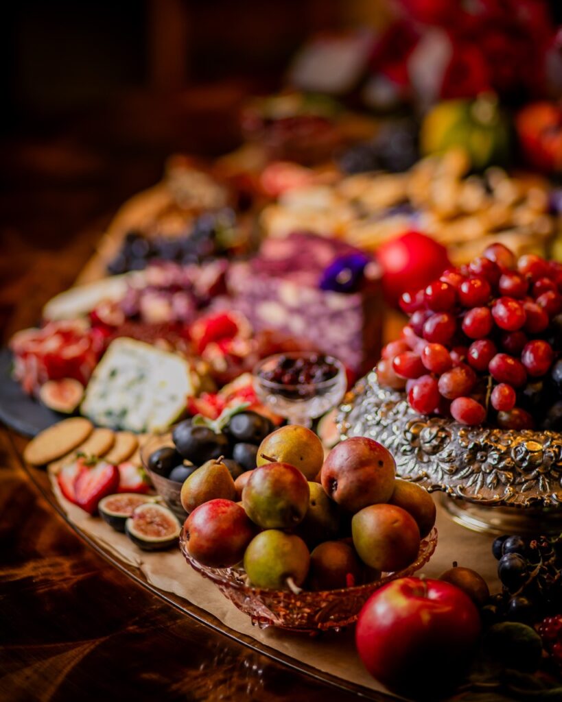 A close up of charcuterie items on a table like figs, berries, cheese, and meats.