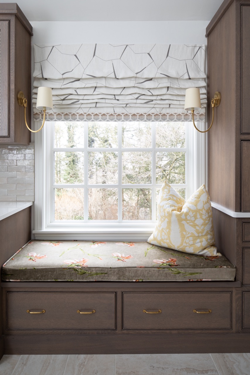 A wooden window seat with a white and yellow striped pillow.