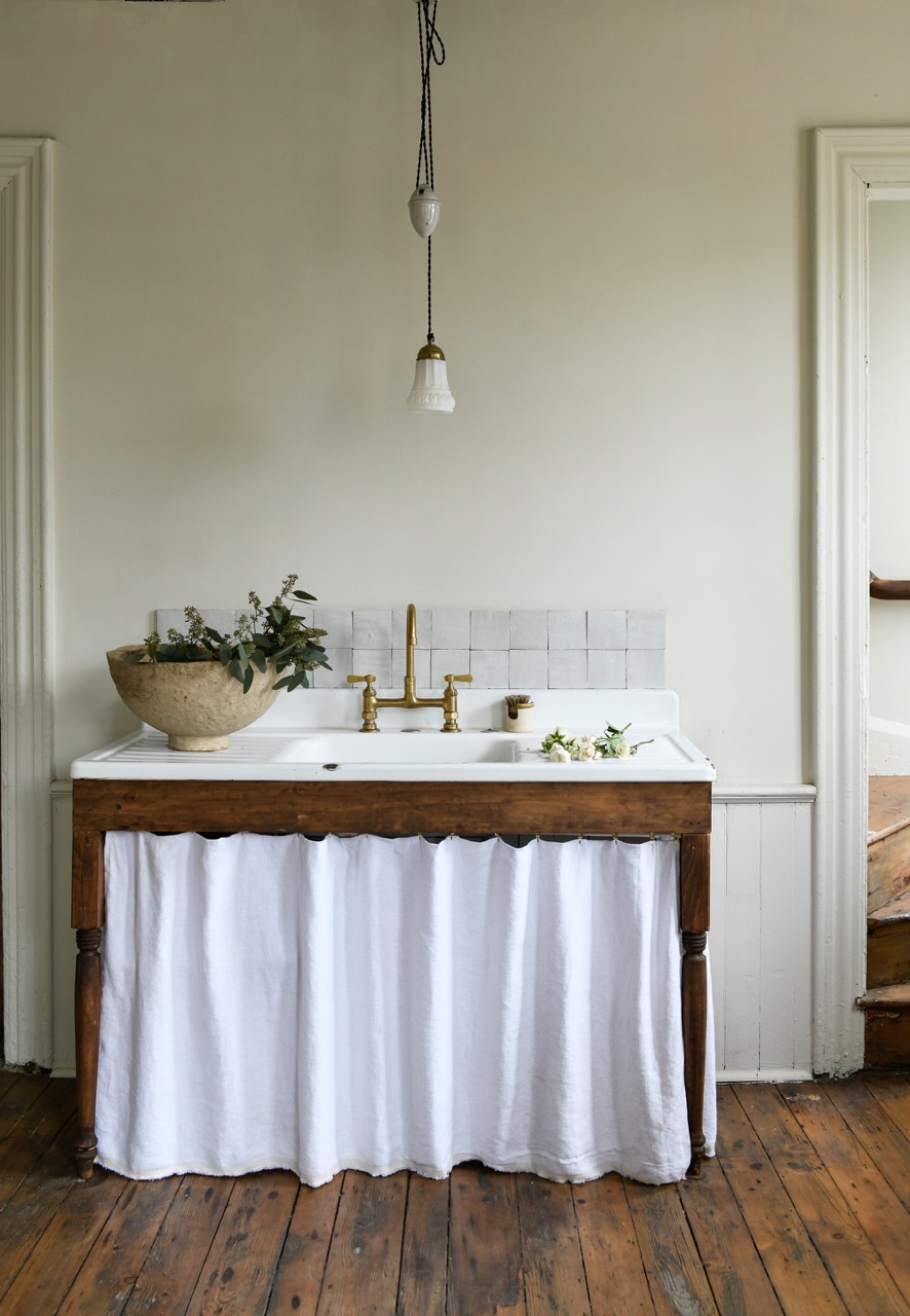 A large farmhouse sink with a white top and white cloth in front of the sink. 