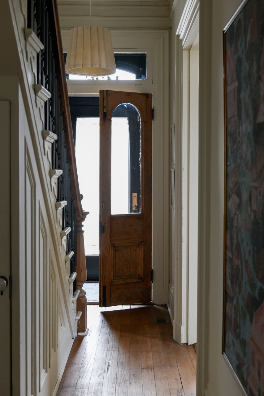 A staircase leads down the left side of the frame with a wooden brown door slightly open straight ahead.