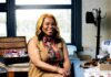 Nisha Blackwell Reinvents Discarded Textiles Nisha Blackwell sits in a khaki dress in front of her work table in her studio.