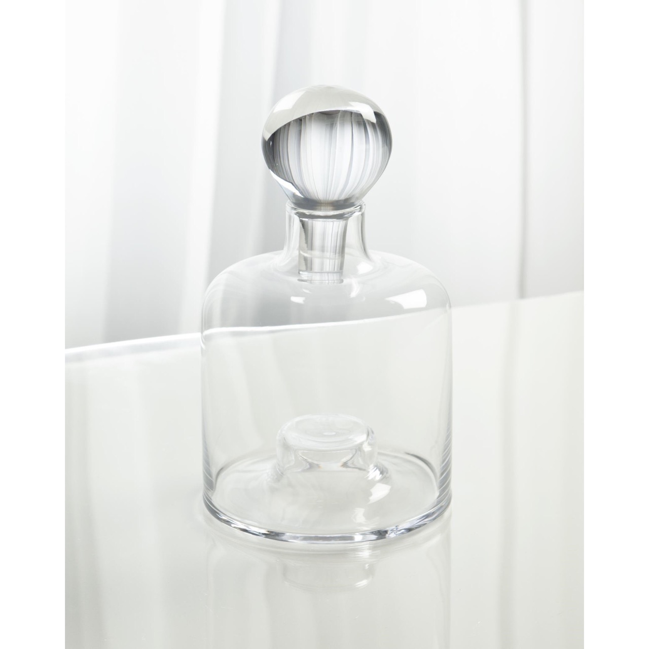 A clear glass decanter sits on a white background as a nostalgia design trend. 