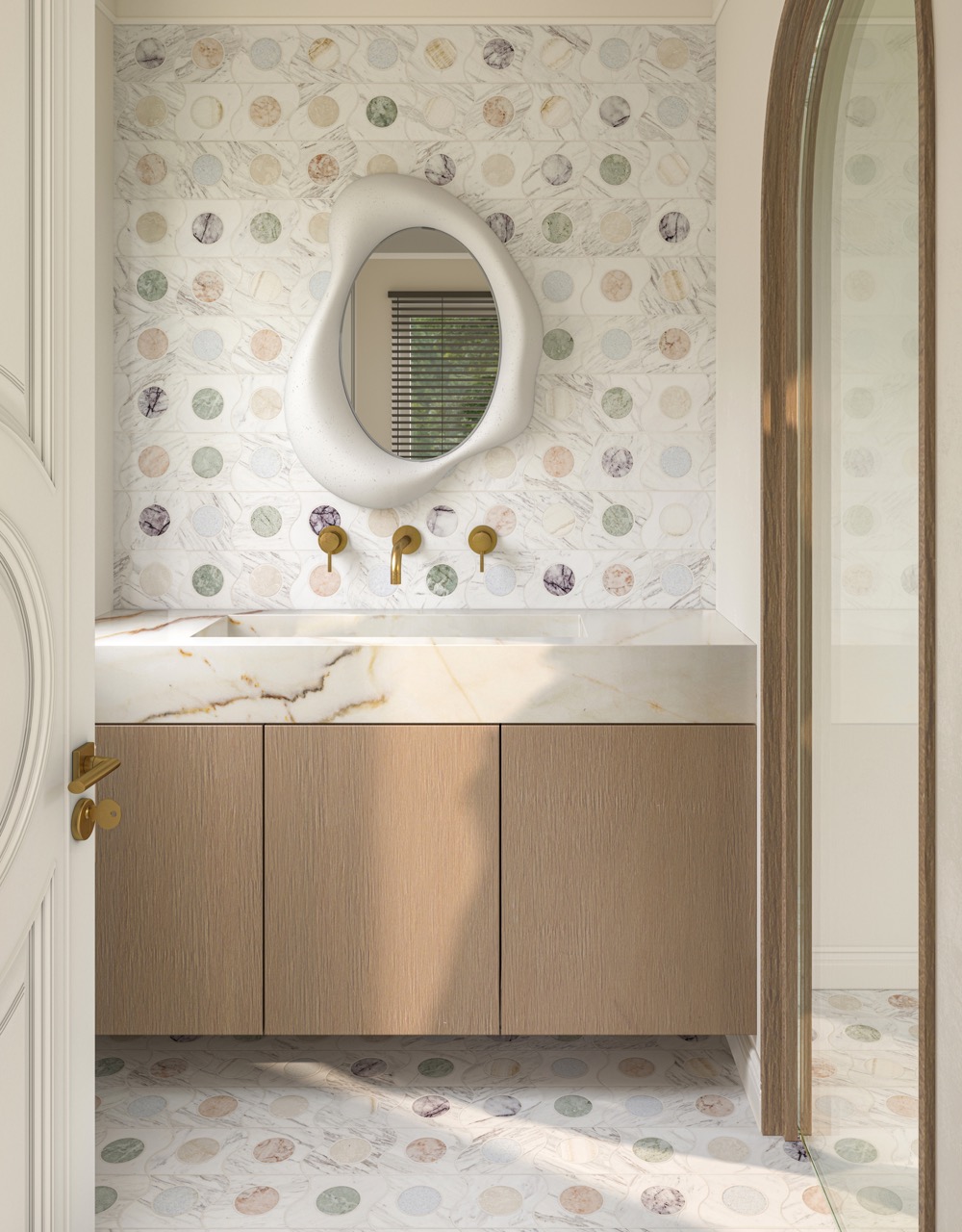 Above a bathroom sink sits an oddly shaped white mirror. 