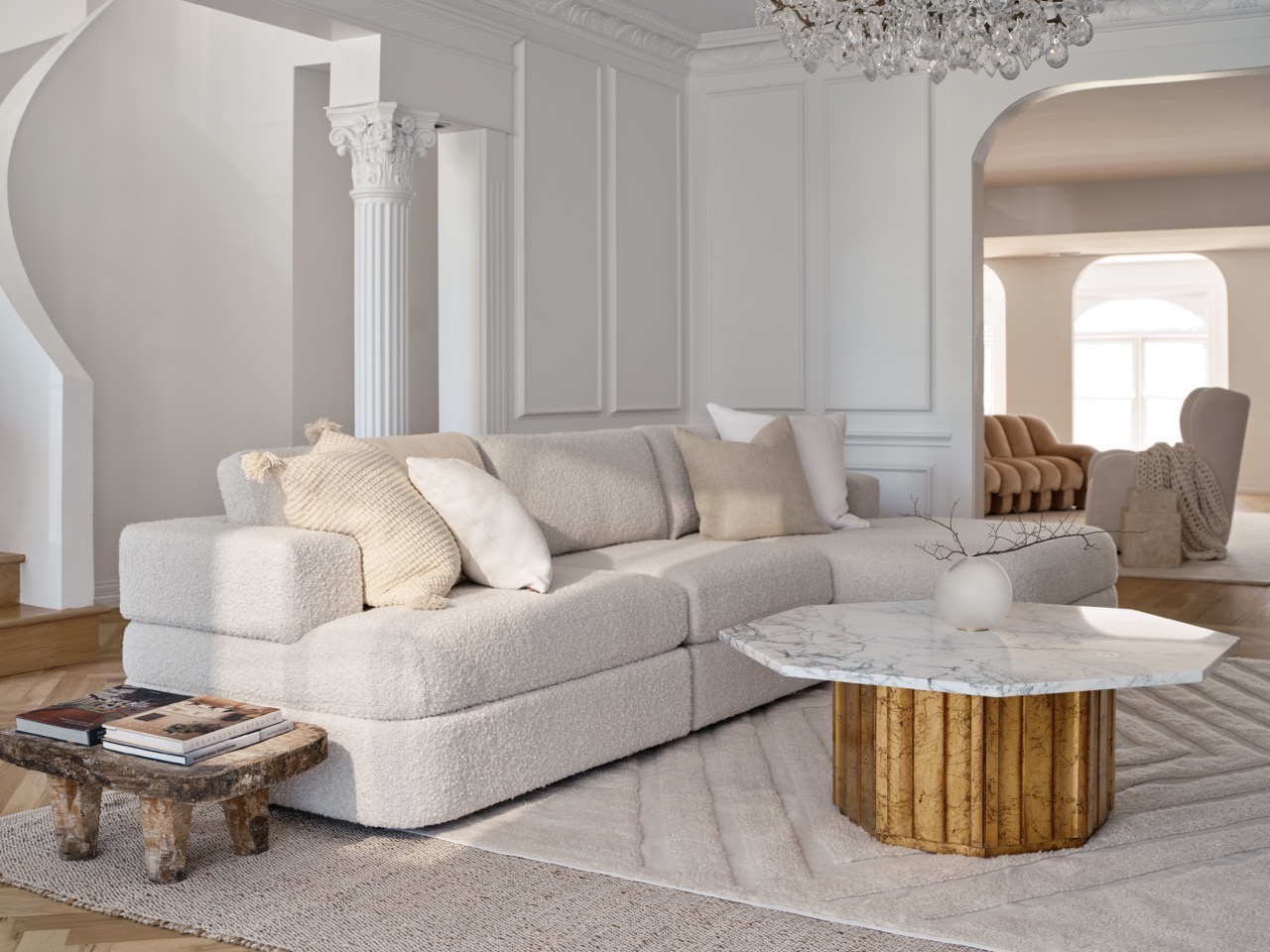 A white and cream colored living room with a white couch and table in the middle. 