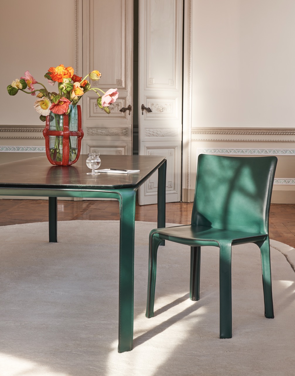 A green glass table and chair from Weisshouse sit in a beige room.