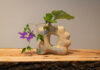 Contemporary Craft Showcases Ikebana with “Gei” A sculpture with flowers coming out of the side, placed on a table