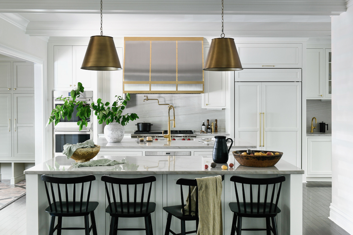 A kitchen table with three black chairs beside it and two hanging lamps