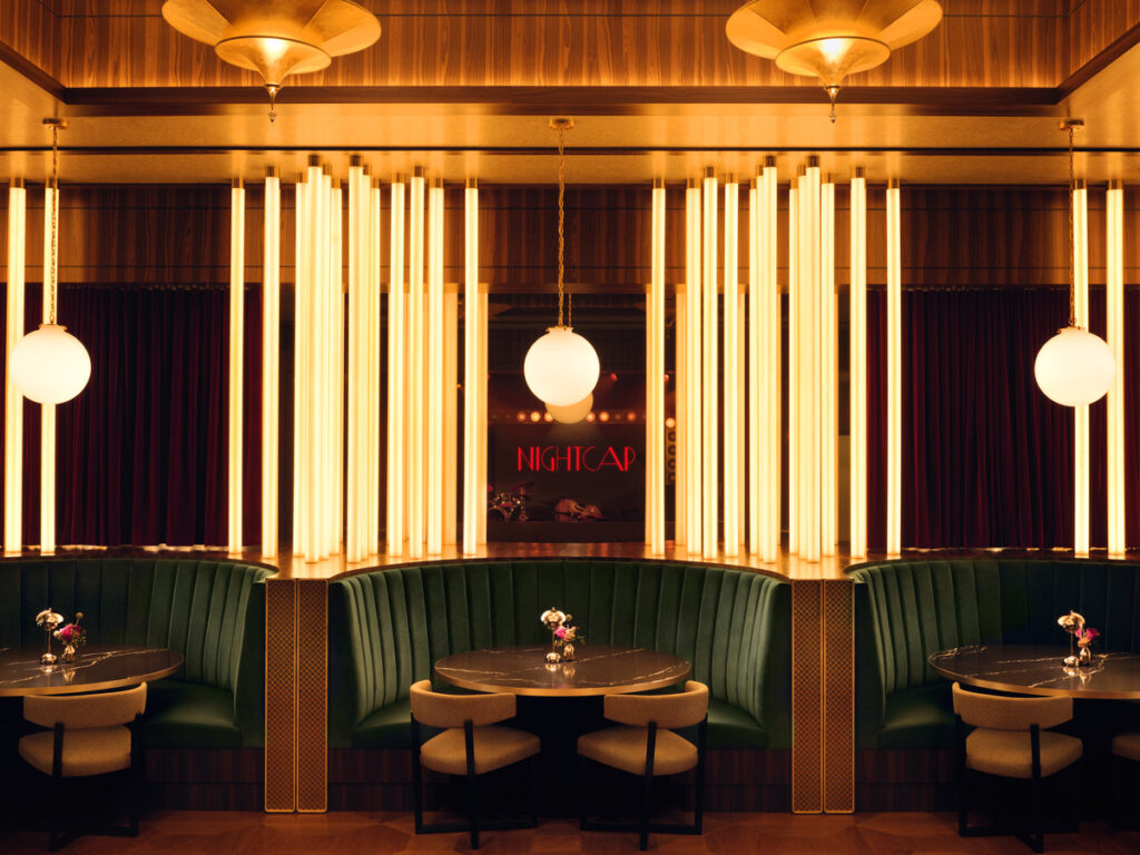 n interior shot of a lounge or bar space with booths featuring green upholstery and wooden accents.