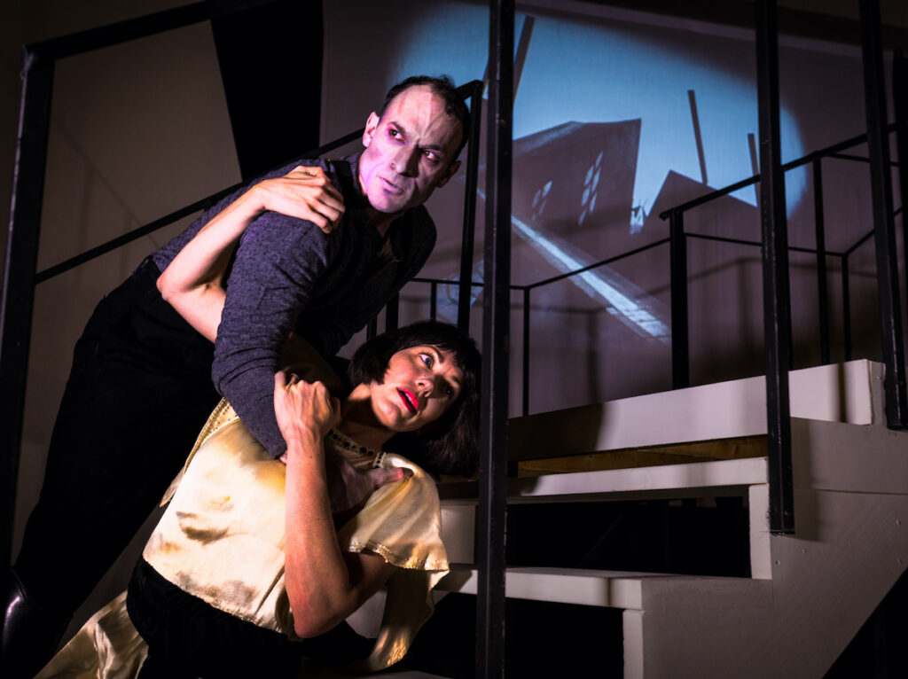 A man and a woman on a staircase in a production of The Cabinet of Dr. Caligari