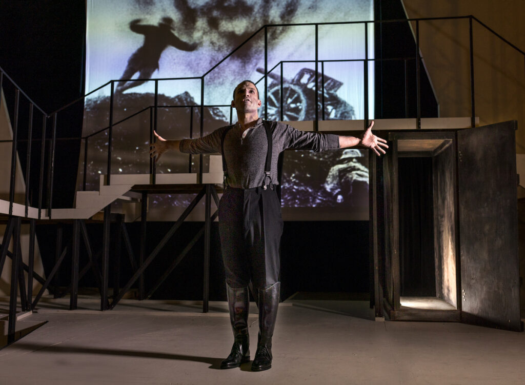 A man stands with his arms out in front of a silent film projection from The Cabinet of Dr. Caligari