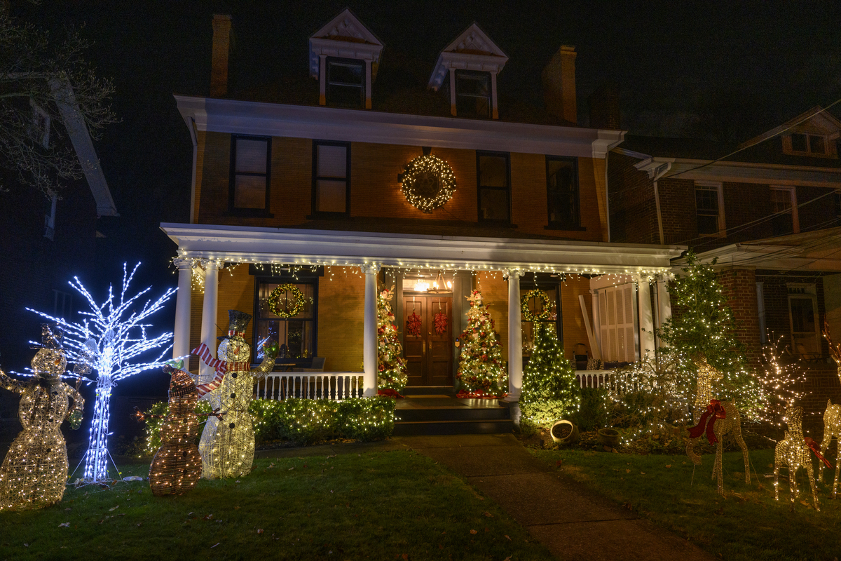 A festively decorated home exterior with string lights, wreaths on the doors, and holiday decorations.