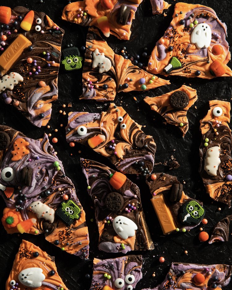 Halloween Candy Bark in various colors with halloween cnady baked in on top.