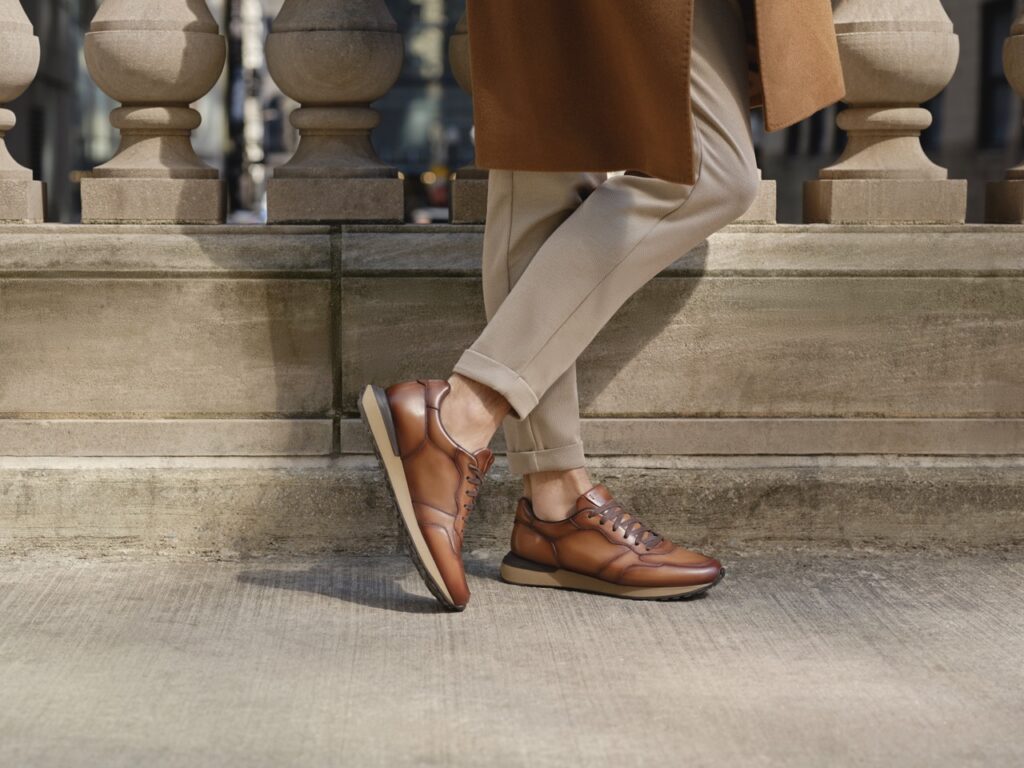 A man walks while wearing brown leather shoes.