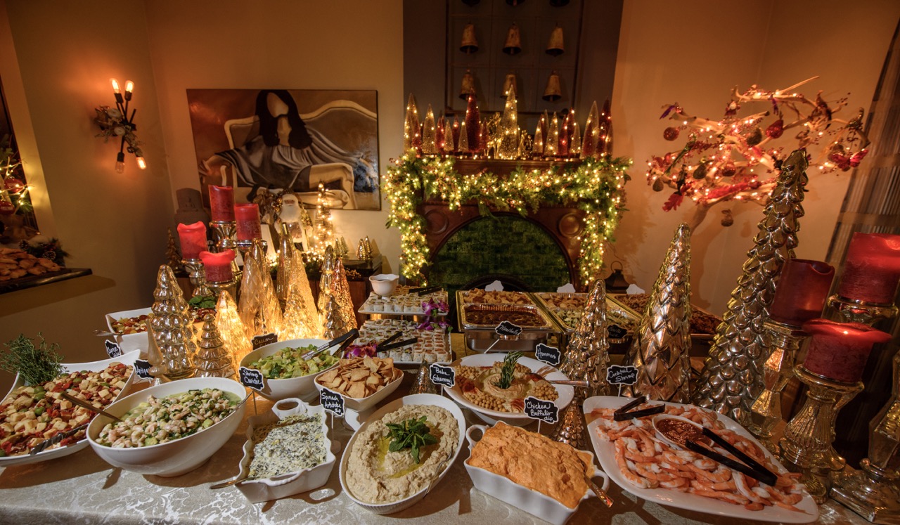 A holiday table at a Christmas party filled with bowls of large party recipes like dips and handhelds. 