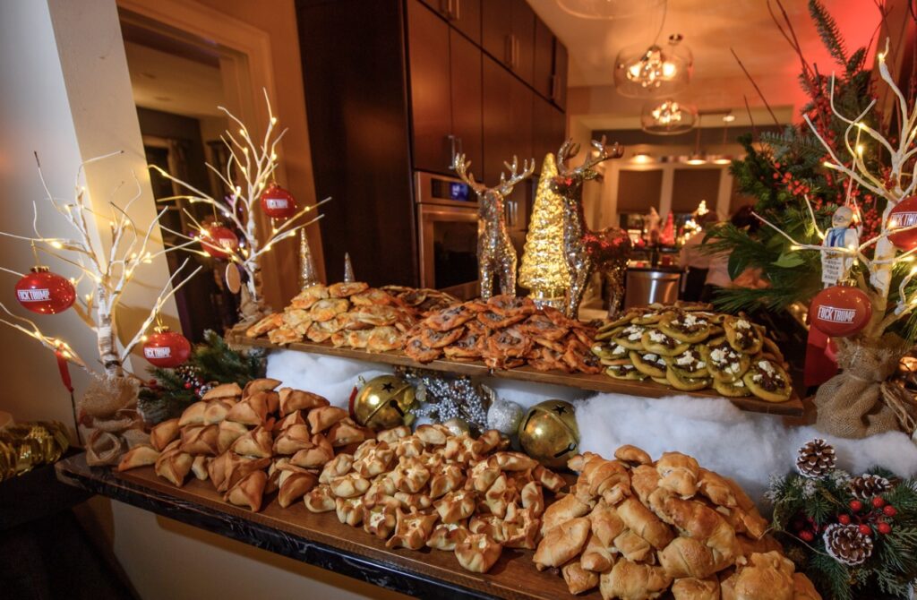 A table full of empanadas and mini pizzas as large party recipes, all sitting amongst Christmas decor. 