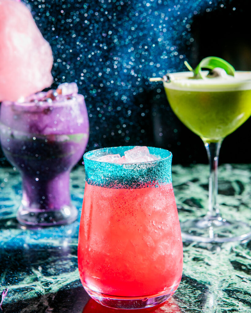 Three colorful mocktail cocktails with tropical drinks in the foreground and background.