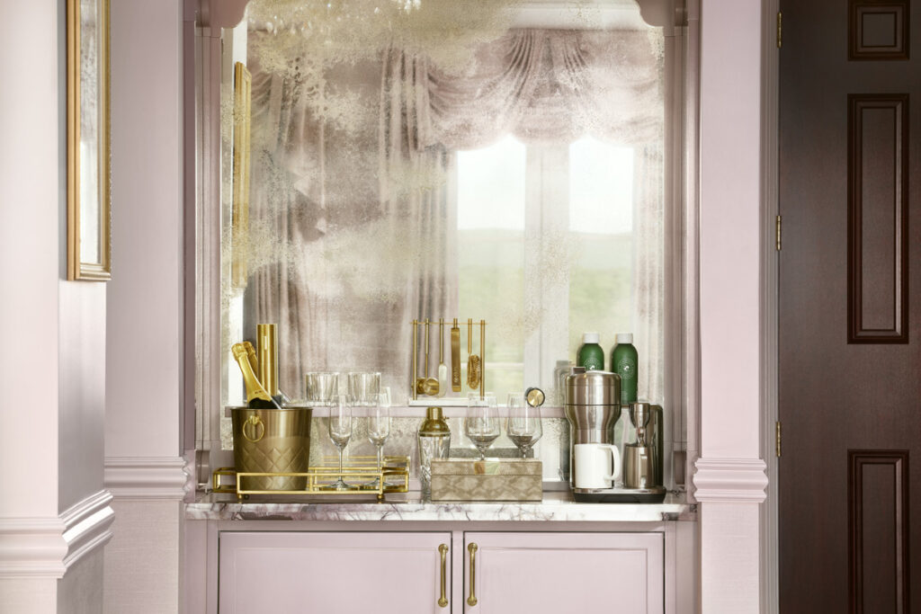 A view of the sleek pink-themed bar inside the resort, showing gold-toned containers and glassware on polished countertops.