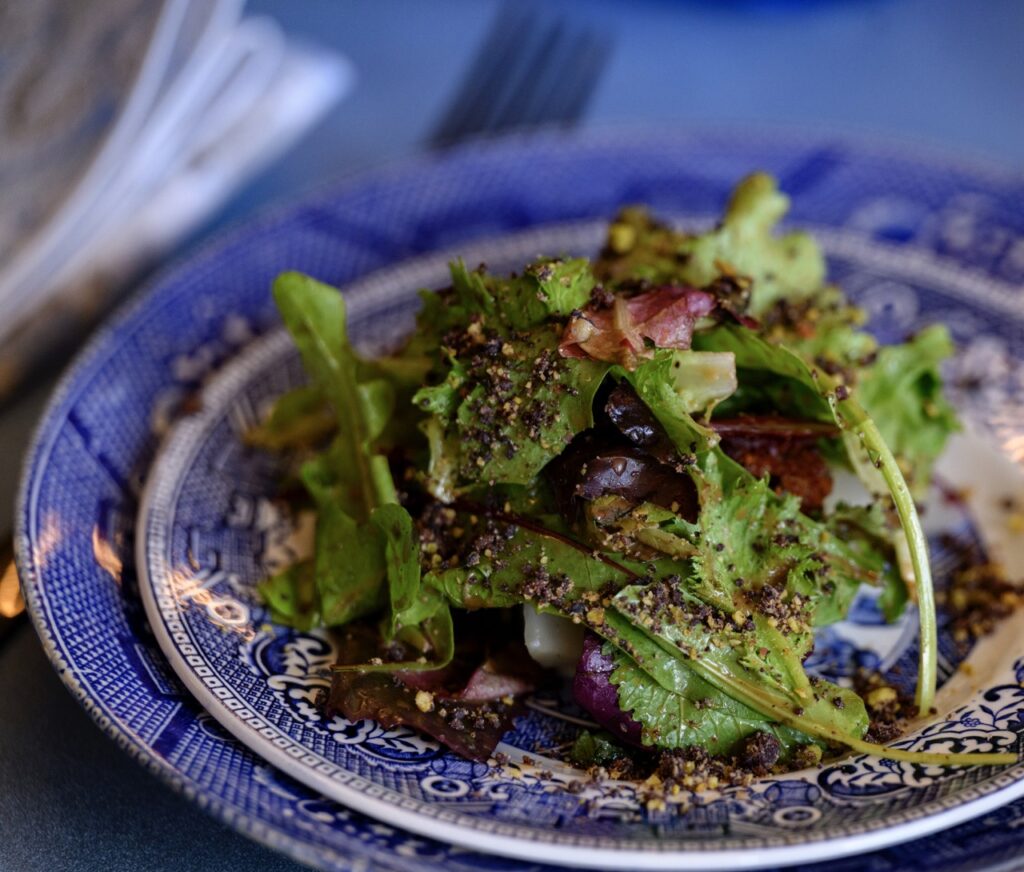 A plate patterned plate with a salad on top of it.