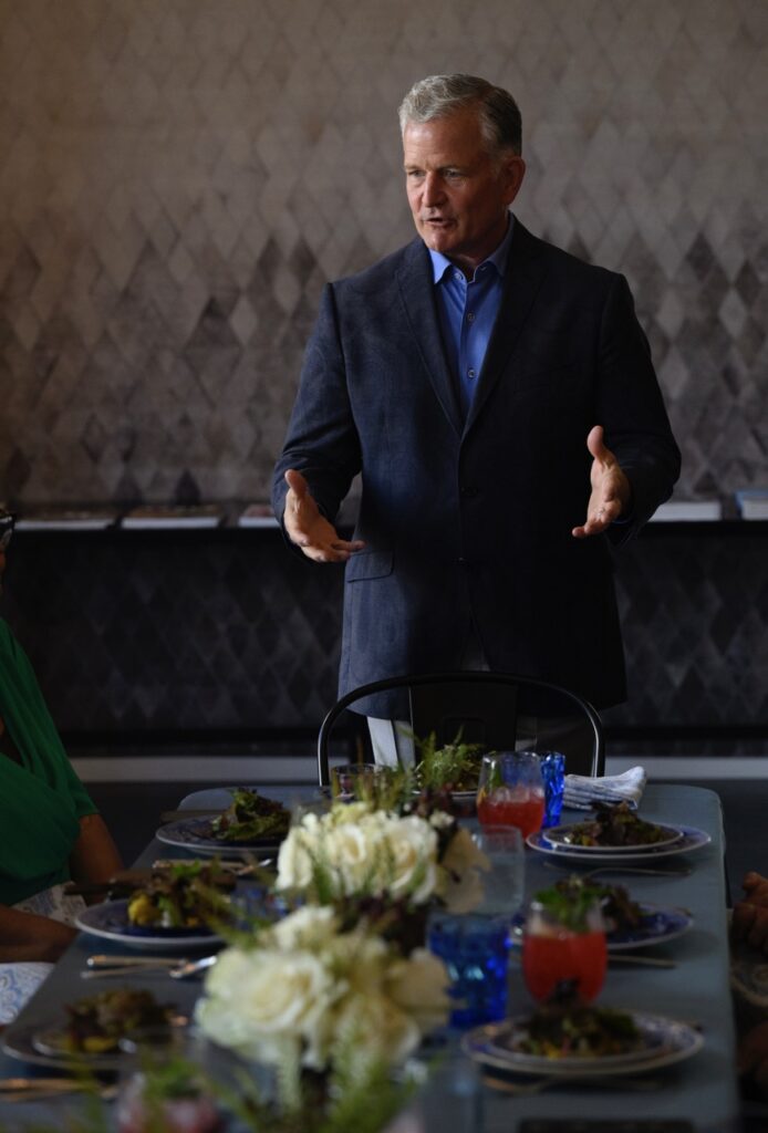 A man in a suit and tie addresses a table of Pittsburgh nonprofit leaders.