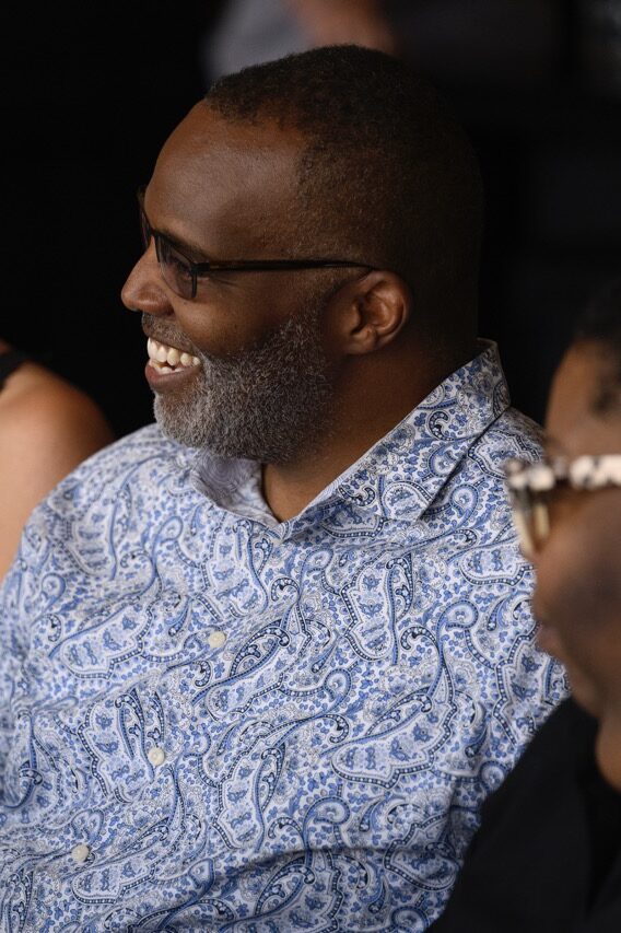 A man in a floral shirt smiles at a woman in a tank top at a nonprofit table.