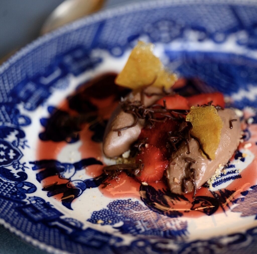 A dessert with strawberry and chocolate drizzle on a blue patterned plate.