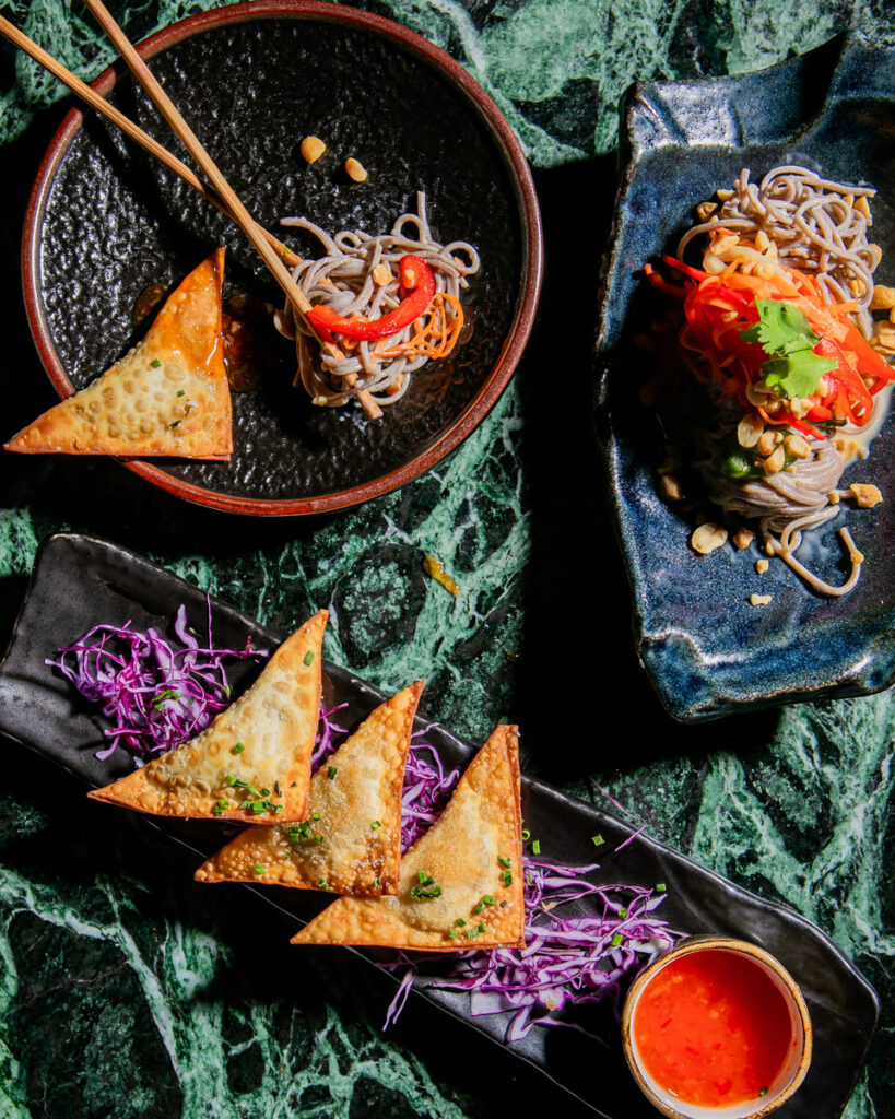 Three Asian-style dishes arranged on a dark textured surface.