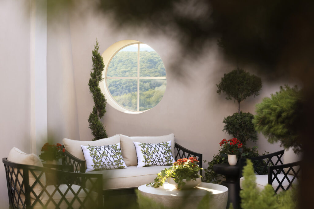 A cozy indoor living area featuring a white sofa with pillows, a wood coffee table with a plant and floral arrangement.