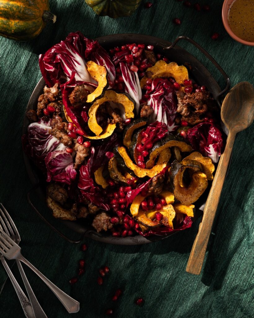 A bowl full of salad featuring roasted acorn squash, apple fennel sausage, and radicchio.