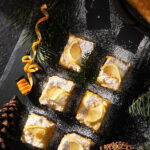 Lemon bars on a black tabletop, covered in powdered sugar