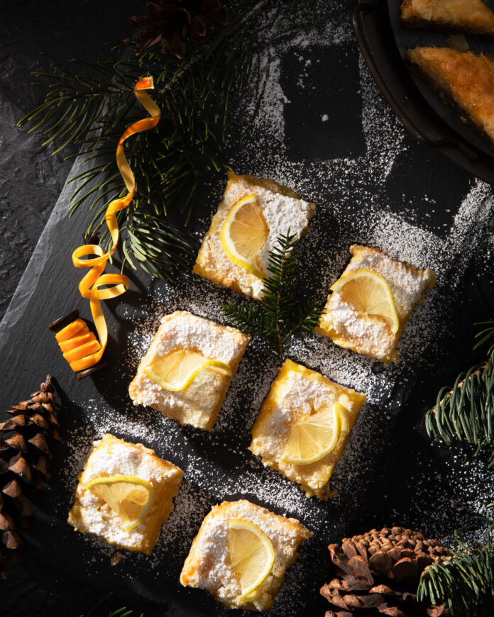 Lemon Curd Bars Lemon bars on a black tabletop, covered in powdered sugar