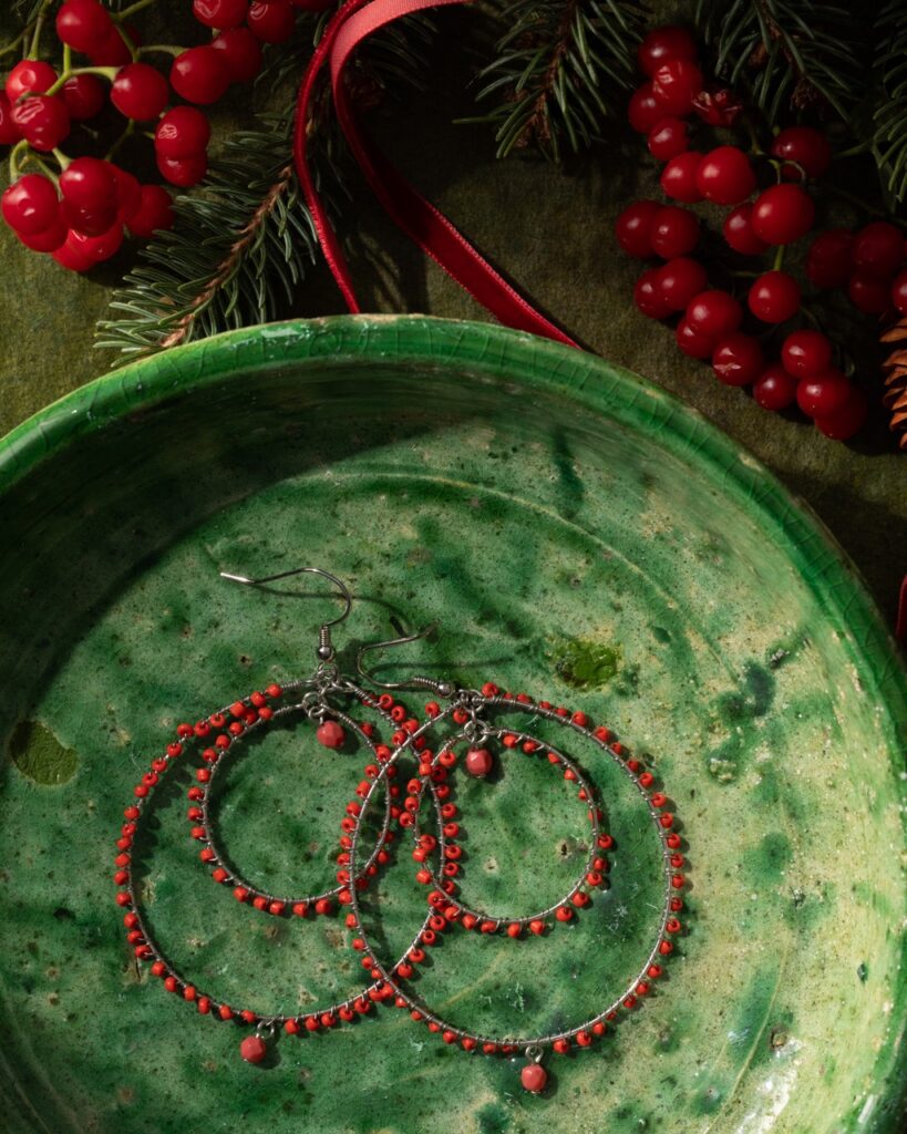 A set of round red hoop earrings sits on a green plate.