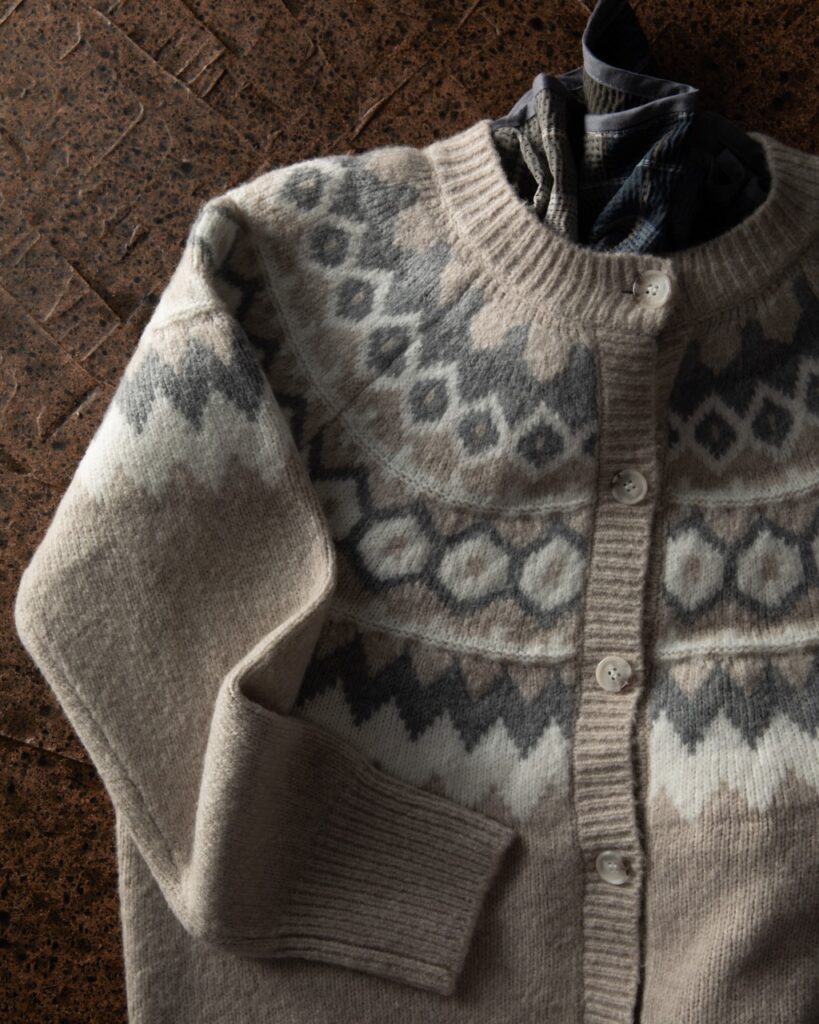 A neutral colored cardigan on a brown table.