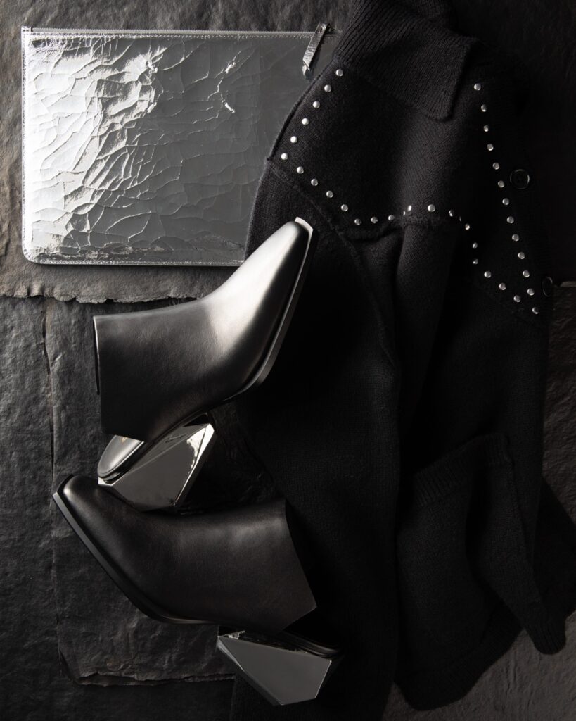 A pair of black dress shoes with silver heels on a black leather jacket.