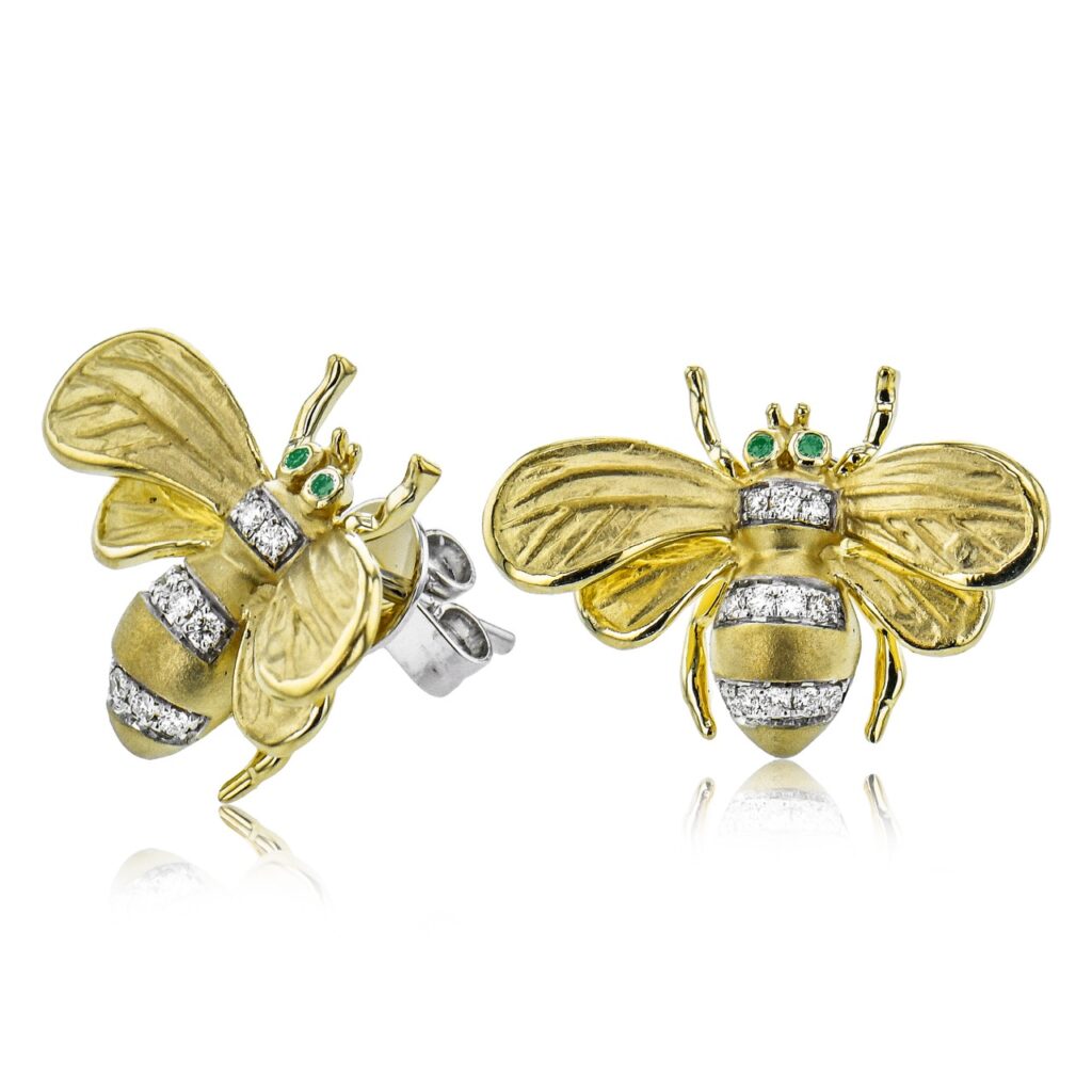Two gold earrings with silver embellishments in the shape of bees.