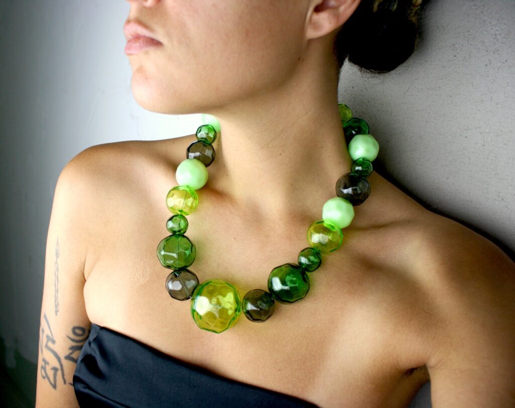 A round green glass necklace on a woman's neck.