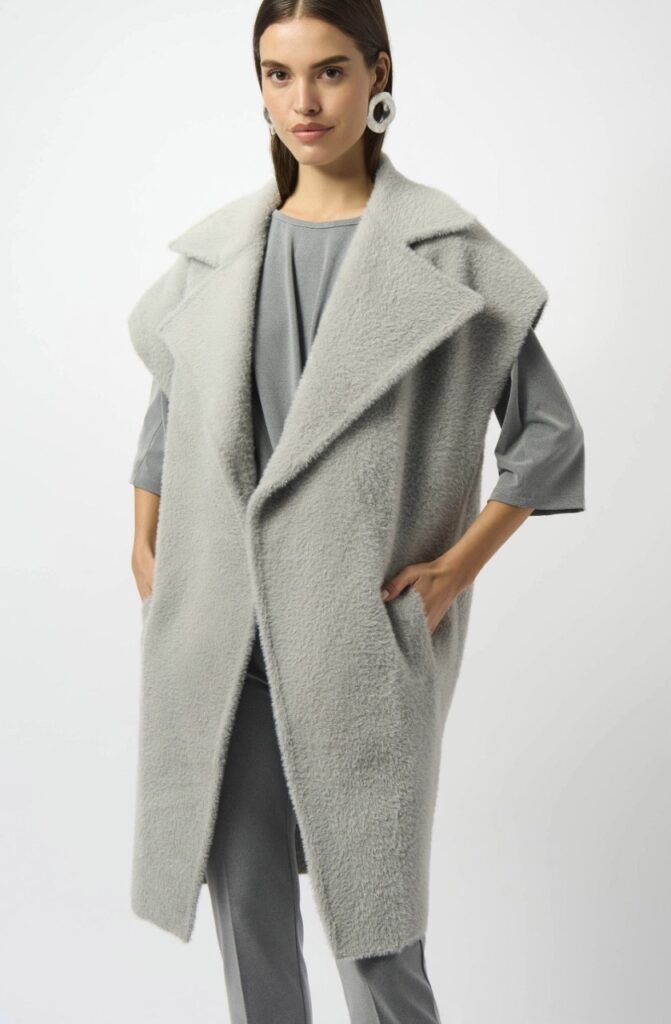 A woman in a long open grey vest jacket.