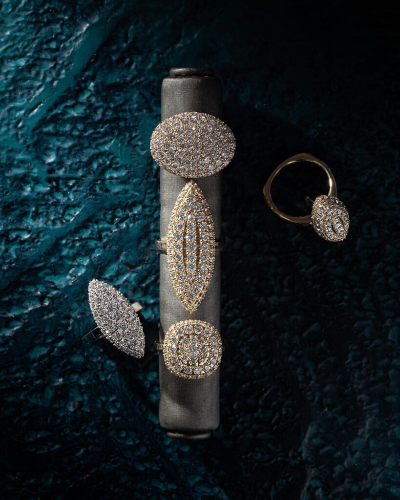 Five rings sit arranged on a cushion on a blue table.