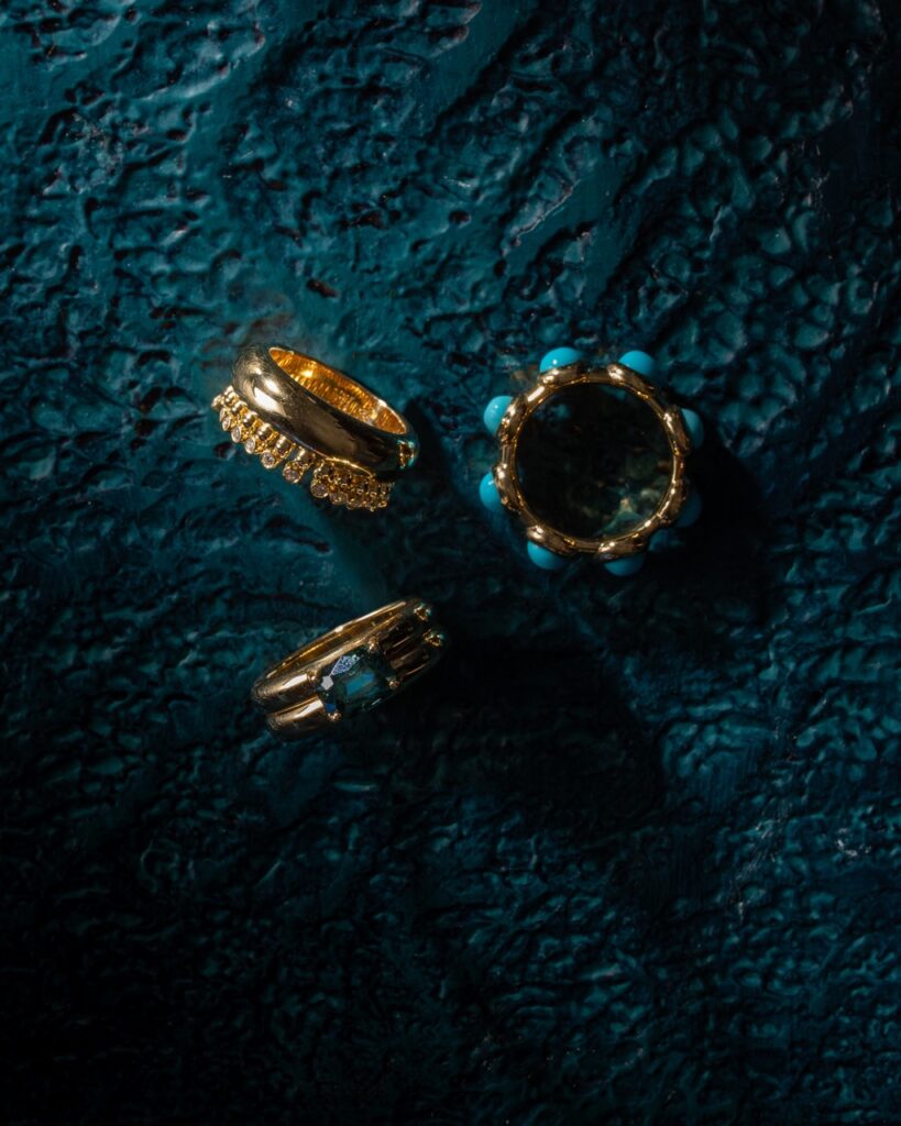 Three gold rings with blue stones on a blue table.