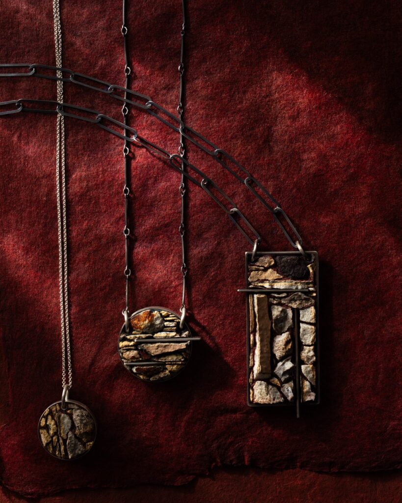 Three stone pendant necklaces on a red table.
