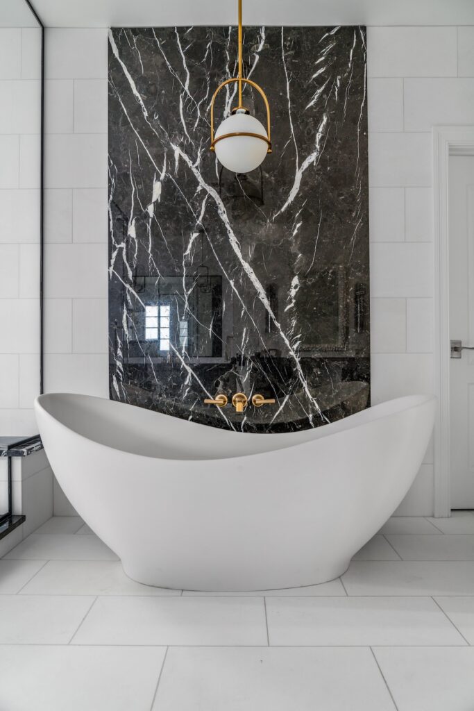 A white ceramic bathtub sits in the middle of a white bathroom.