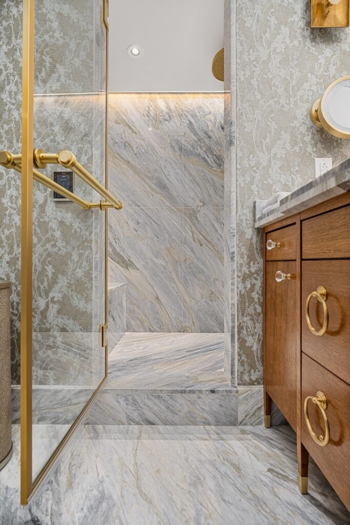 Grey stone walls cover a bathroom with a wood and stone wink to the right. 