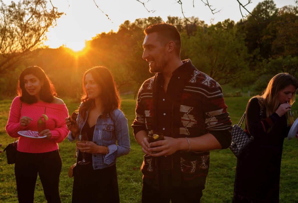 Guests stand outside in the soft amber light of the setting sun 