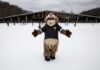 Embrace Winter at Allegheny County Parks A chipmunk mascot with a blue Allegheny County Parks navy blue shirt facing the camera standing on the ice at an outdoor ice rink in Pittsburgh.