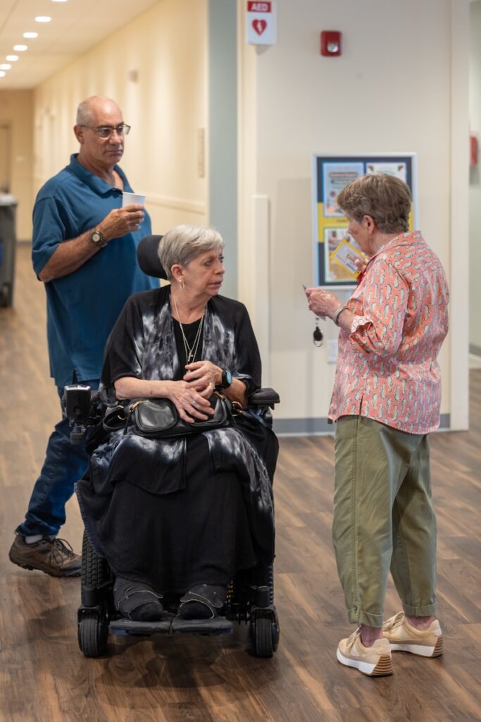 A woman speaks to another woman in a wheelchair.