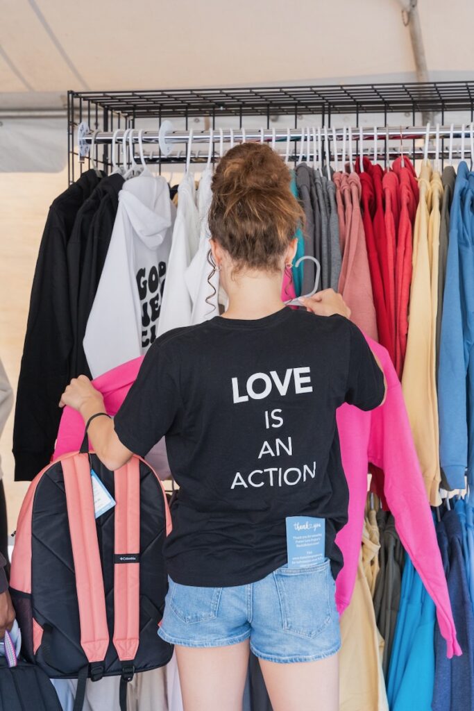 A woman with a black shirt looking through a clothing rack.