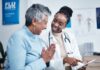 Giving Guide 2025: Metro Community Health Center Black woman, doctor and elderly patient with good news, tablet and results for health, advice and report. Happy african medic, mobile touchscreen or healthcare with smile, tech or support in hospital.