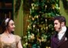 Giving Guide 2024: City Theatre A woman in a dress and man in a dress coat take each other's hand in front of a Christmas tree with lights on it.