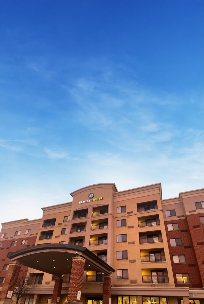 The outside of a large brown building sits beneath a blue sky with whispy clouds.